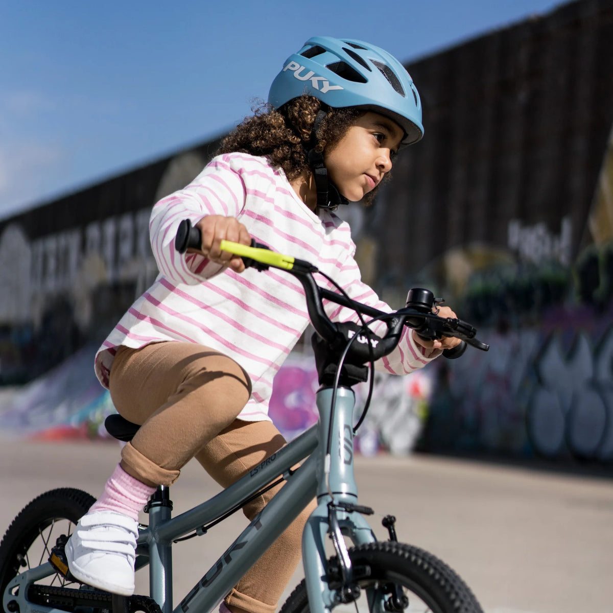 Child who rides a bike with a blue bike helmet from Puky on the head.