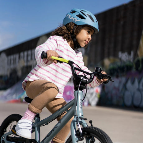 Barn som cyklar med en blå cykelhjälm från Puky på huvudet.