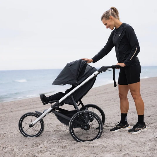 Thule Glide 3 joggingvagn på stranden med barnet i sittdelen, hyr hos Parently